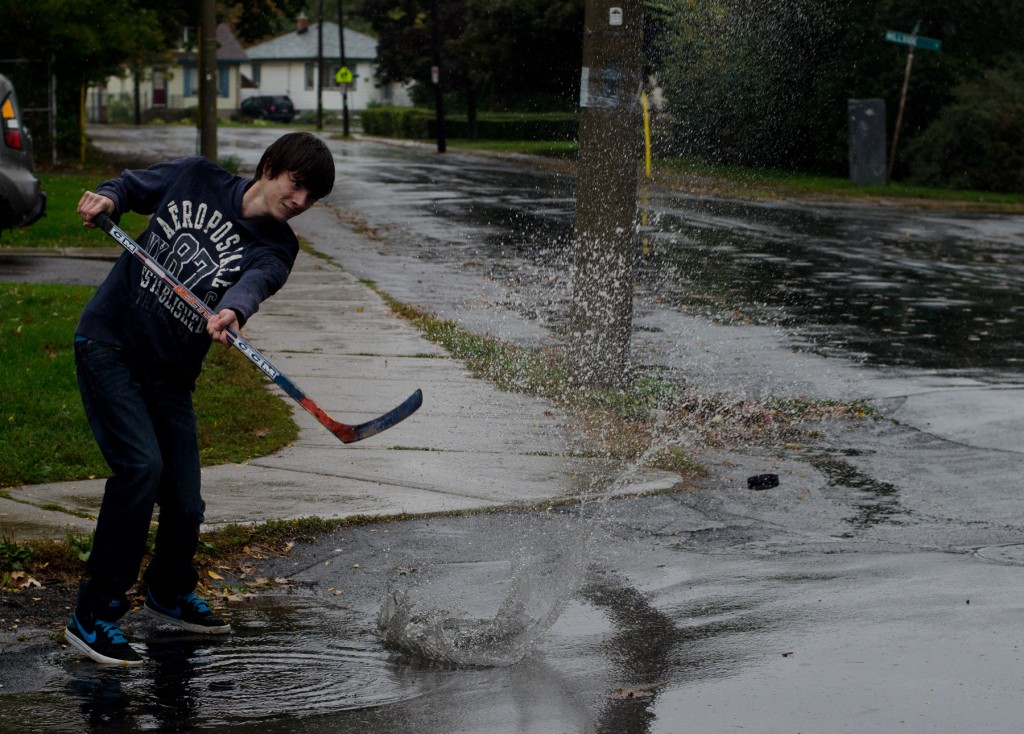 BELLEVILLE, Ont (10/05/2013)- Cody Conlin shoots the puck out of a puddle while playing street hockey on Holloway Street in Belleville. Conlin and his friend Dylan Langabeer are next door neighbors, and continued their game despite the heavy rain which fell throughout the morning this past Sunday. Photo by James Wood