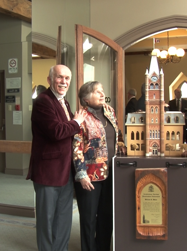 Bill White poses beside his wife Pat and a model of Belleville's city hall. Photo by Cam Kennedy